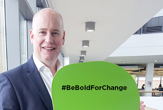 man holding sign with 'be bold for change' on it